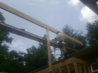 Carpenter setting a ridge beam over a new addition frame — Ice Dam Removal by Roofing Brothers in Oakridge