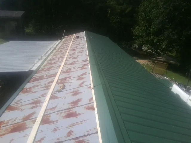 Old rusted panels beside newly installed green metal roofing — Wind Damage Roof Repair by Roofing Brothers in Oakridge