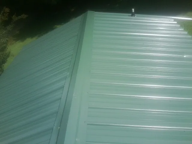 New green metal panels meeting at the ridge of a roof — Flat Roof Repair work by our crew in Oakridge