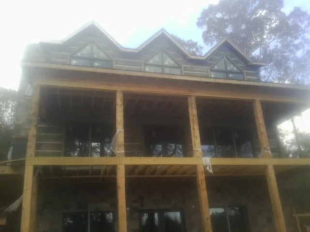 Dormers and porch framing on a large log home under construction — Roof Coating work by our crew in Oakridge
