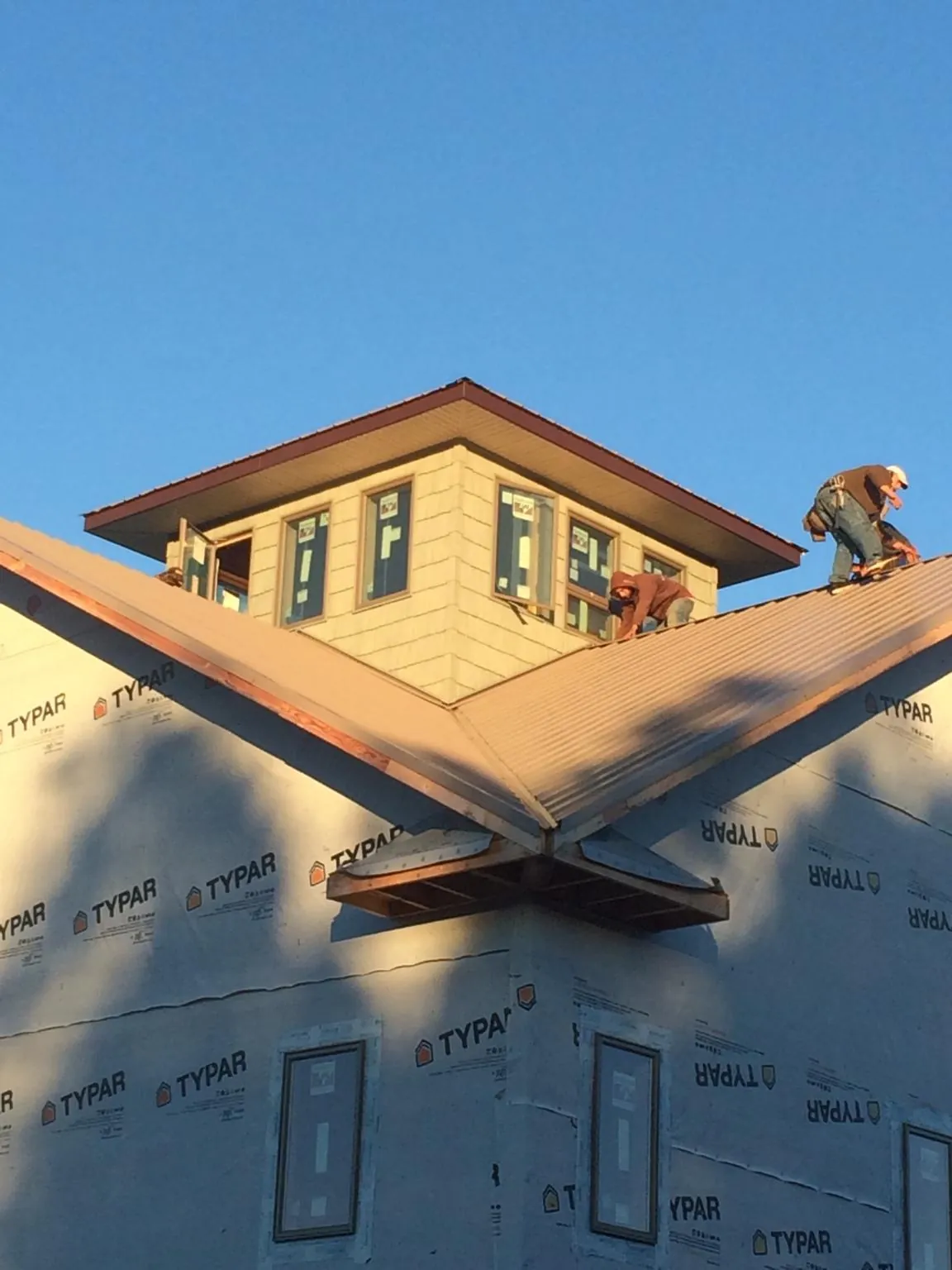 Roofers working around a rooftop cupola on a new metal roof at sunset — Roof Waterproofing in Oakridge by Roofing Brothers